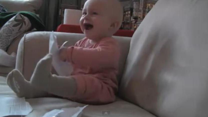 baby laughs at ripping paper