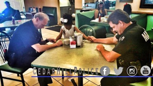 little girl prays with two officers
