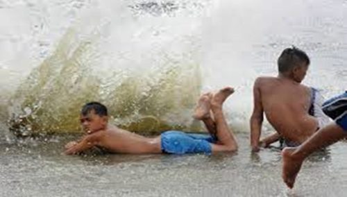 Children play in the waves of Manila Bay as the storm pounds.