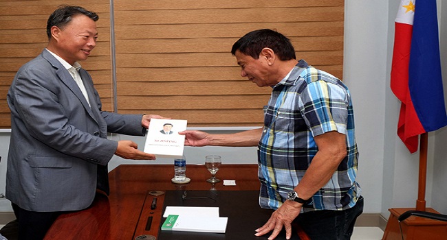 In this photo released by the Office of the City Mayor of Davao City, presumptive president-elect Rodrigo Duterte, right, receives a copy of the book on Chinese President Xi Jinping from Chinese Ambassador to the Philippines Zhao Jianhua during a courtesy call at Davao City in the southern Philippines, Monday, May 16, 2016. Presumptive Philippine President-elect Rodrigo Duterte said Monday he would offer Cabinet posts to communist rebels, a move to amend the constitution to give more power to the provinces and reimpose the death penalty in some of his first policy pronouncements since winning last week's election based on an unofficial count. (Office of the City Mayor Davao City via AP) MANDATORY CREDIT
