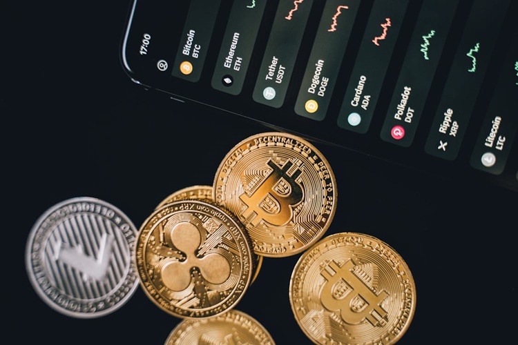 Cryptocurrency symbols on gold coins next to a smartphone