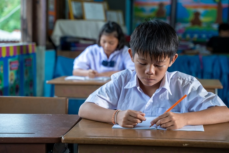 Asian elementary students in uniform studying together at classr